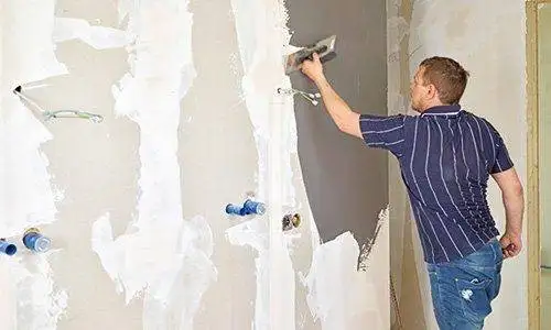 Mit einer Traufel wird die eingefärbte Spachtelmasse auf die zuvor grundierte Gipskartonfläche aufgezogen.