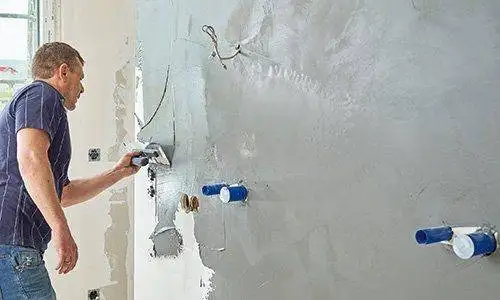 Mit einer Traufel wird die eingefärbte Spachtelmasse auf die zuvor grundierte Gipskartonfläche aufgezogen.