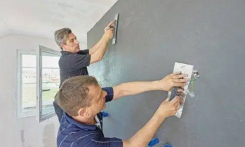 Zwei Männer verpressen mit Traufeln die Spachtelmasse für das die Badezimmer Betonoptik.