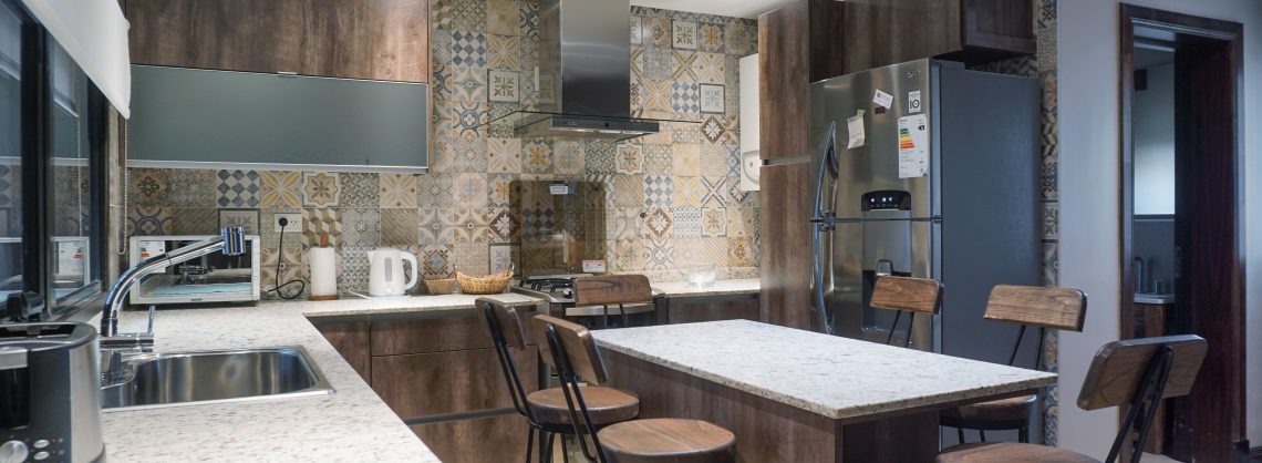 Einbauküche mit auffallendem, braun-blau gemustertem Fliesenspiegel an der Wand.