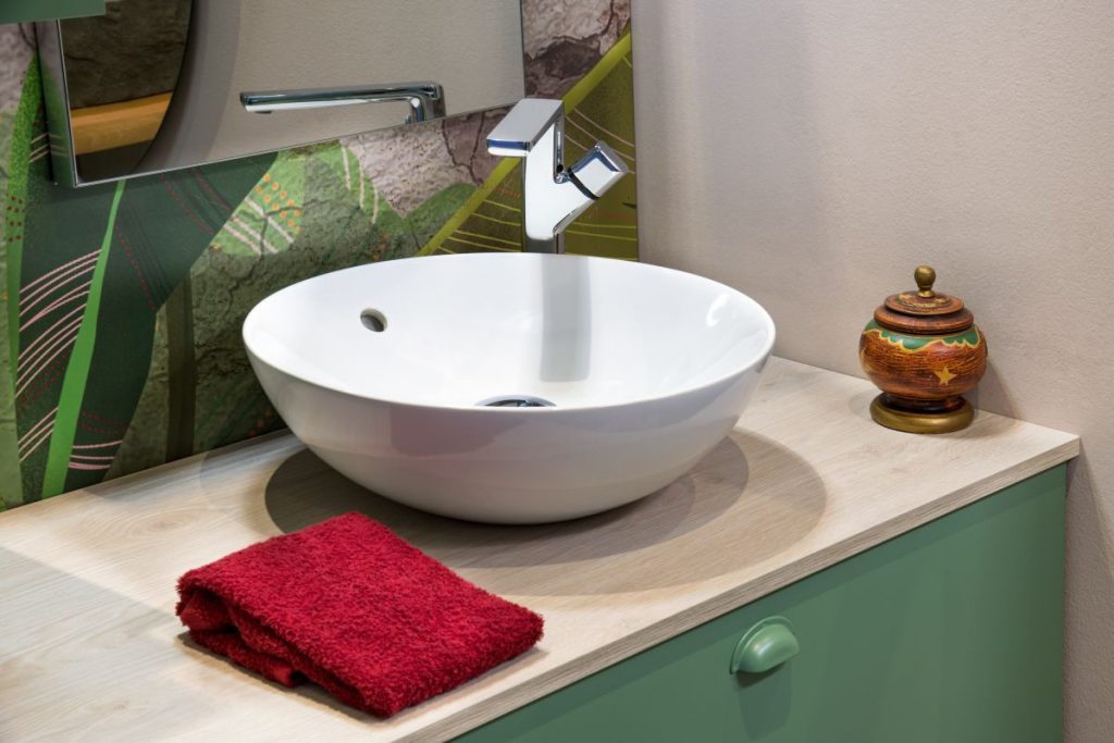 Aufgesetztes Waschbecken auf einem grünen Waschtisch.