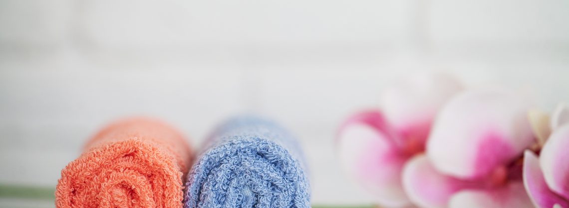 Handtücher zusammengerollt auf Badezimmerfläche.