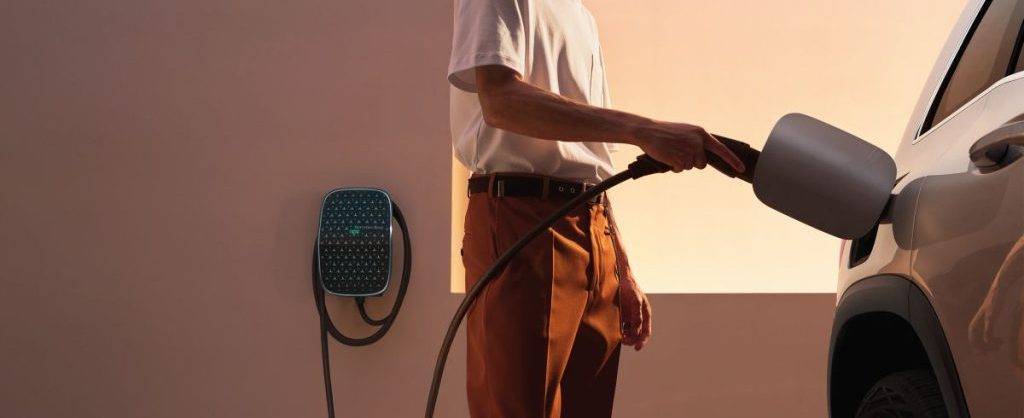 Junger Mann lädt sein E-Auto.