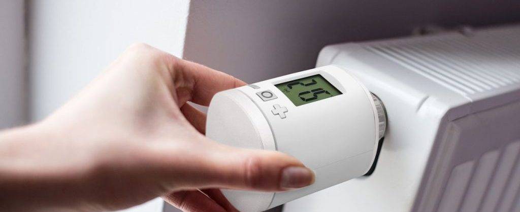 Frauenhand bedient Thermostat an Heizung.