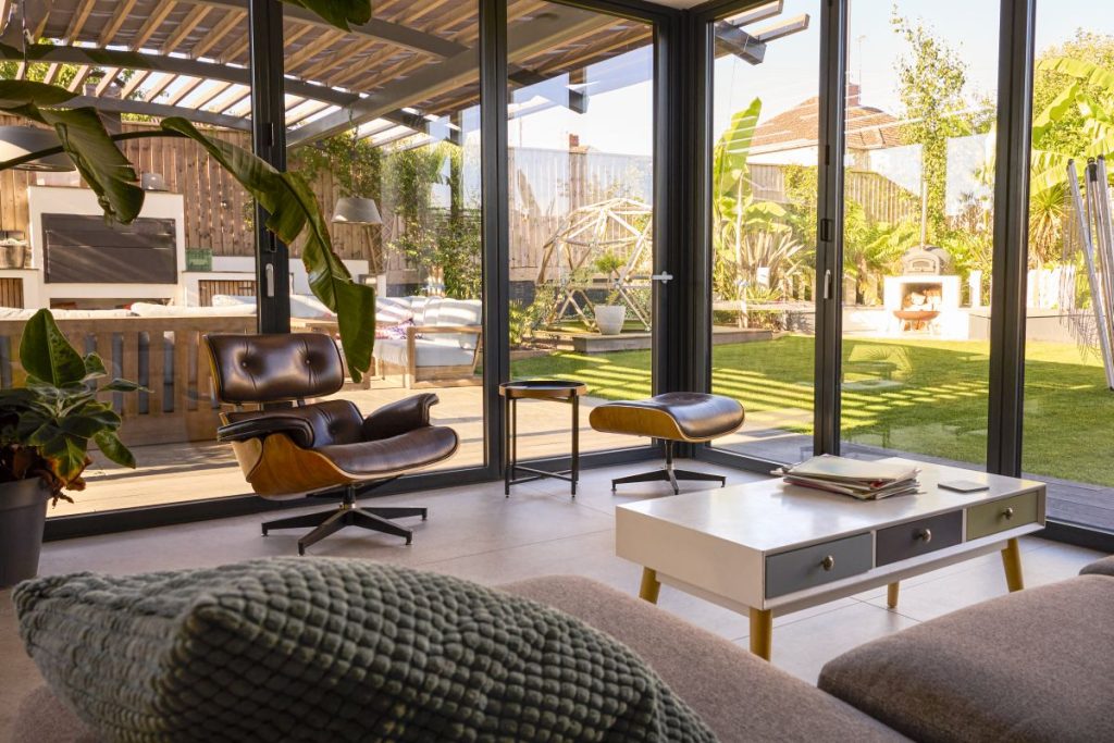 Zimmer mit Glaswänden und Blick auf Sitzgelegenheiten im Freien und Garten im modernen Haus