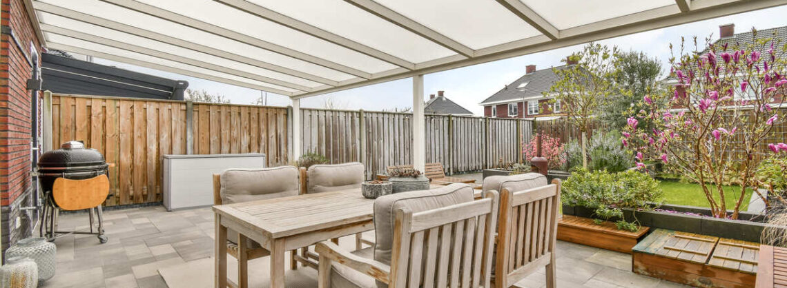 Terrasse mit Holzmöbel, Grill & einer Überdachung