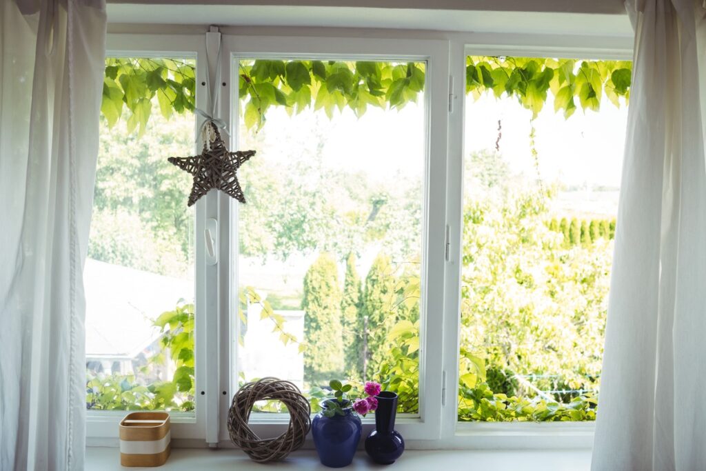 Fenster mit Deko auf dem Fensterbrett und Blick ins grüne