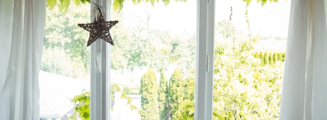 Fenster mit Deko auf dem Fensterbrett und Blick ins grüne