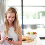 Frau in der Küche mit Smartphone